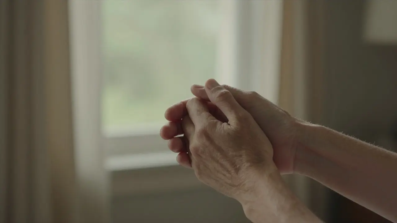Two hands gently holding each other in natural light.