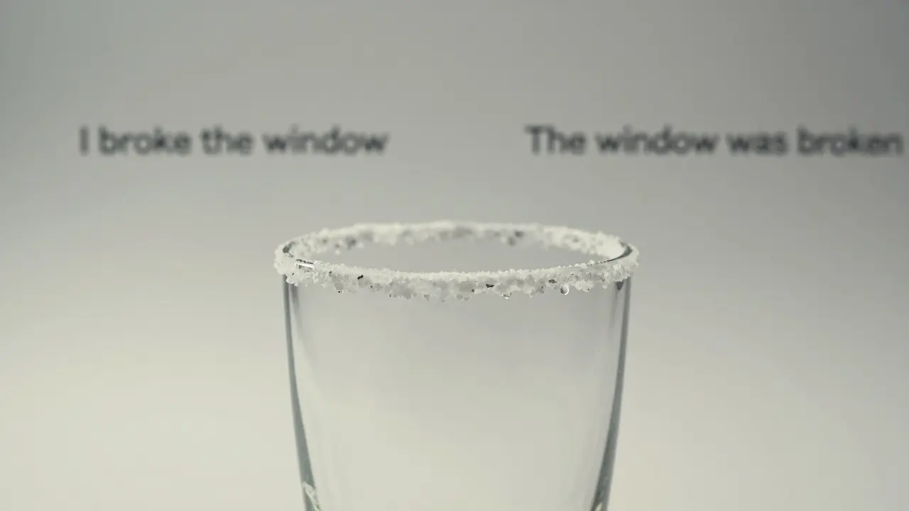 A glass with a salted rim holds a single droplet, symbolizing the quiet power of passive voice.