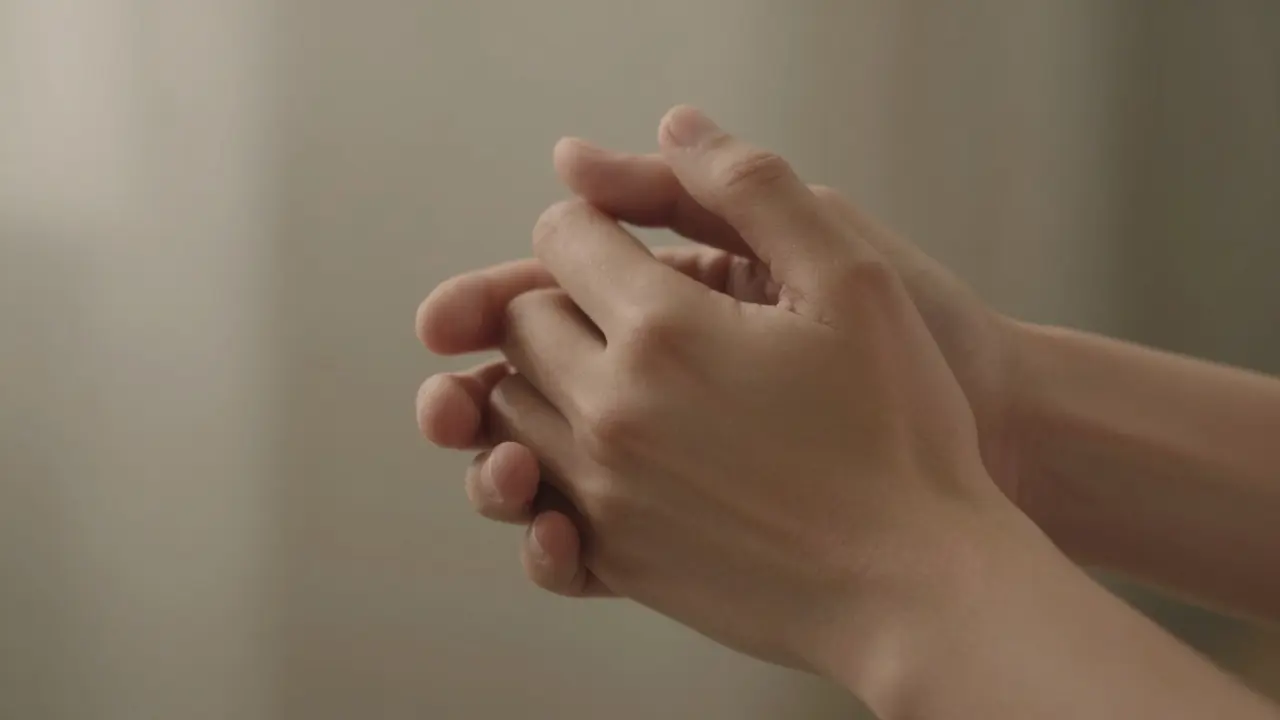 Two hands gently holding each other in a calm, blurred environment, conveying quiet intimacy.